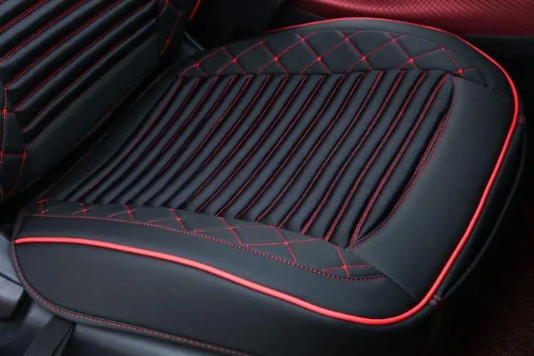 Close up of a car leather seat with red trim and stitching