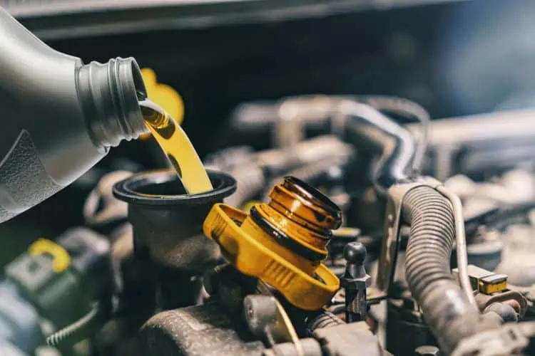 Close up of person pouring oil into car engine