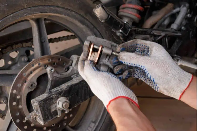 Man installing new brake pads onto motorcycle