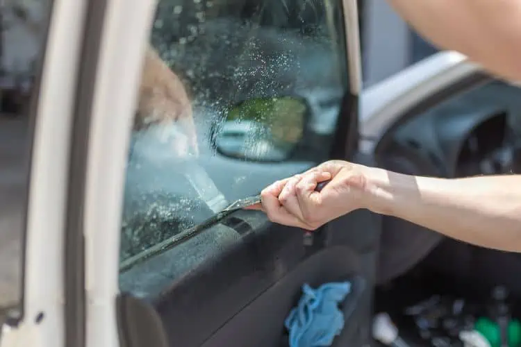 Person wiping the inside passenger window with a cloth 