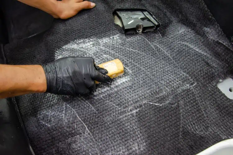 Man scrubbing car carpet shampoo into carpet