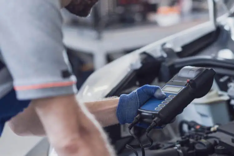 Mechanic  standing over car engine using an OBD 2 scanner