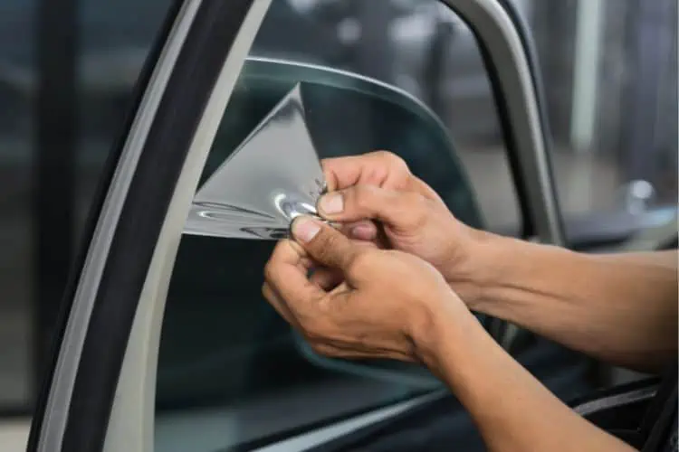 Person peeling off tint from car window in one go