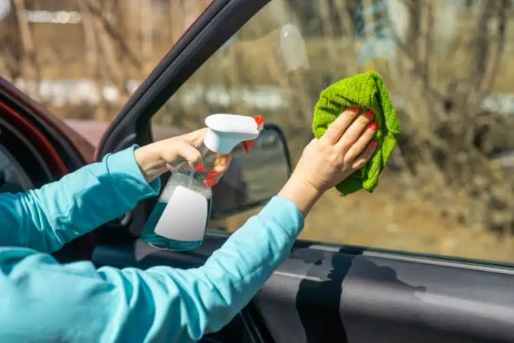 Person wiping the inside passenger window with a cloth 