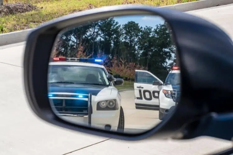 Police cars with flashing lights on in rear view mirror