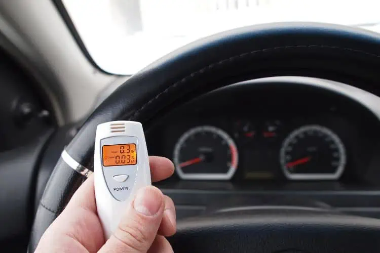 Portable breathalyzer in the hand of a driver at the wheel