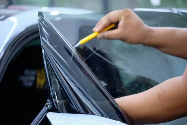 Professional applying window tint film to car window