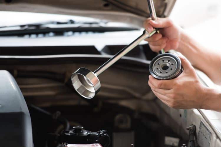 Man holding oil filter wrench and oil filter